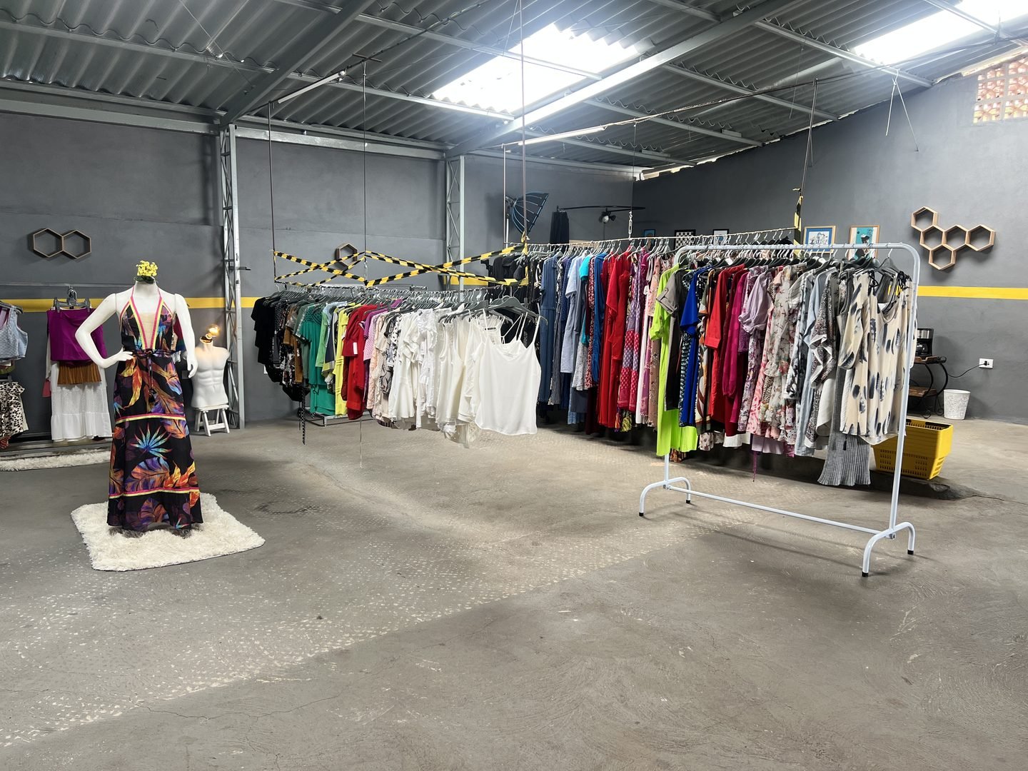 O salão do Brechó Oficina, com araras de roupa e um manequim de vestido longo