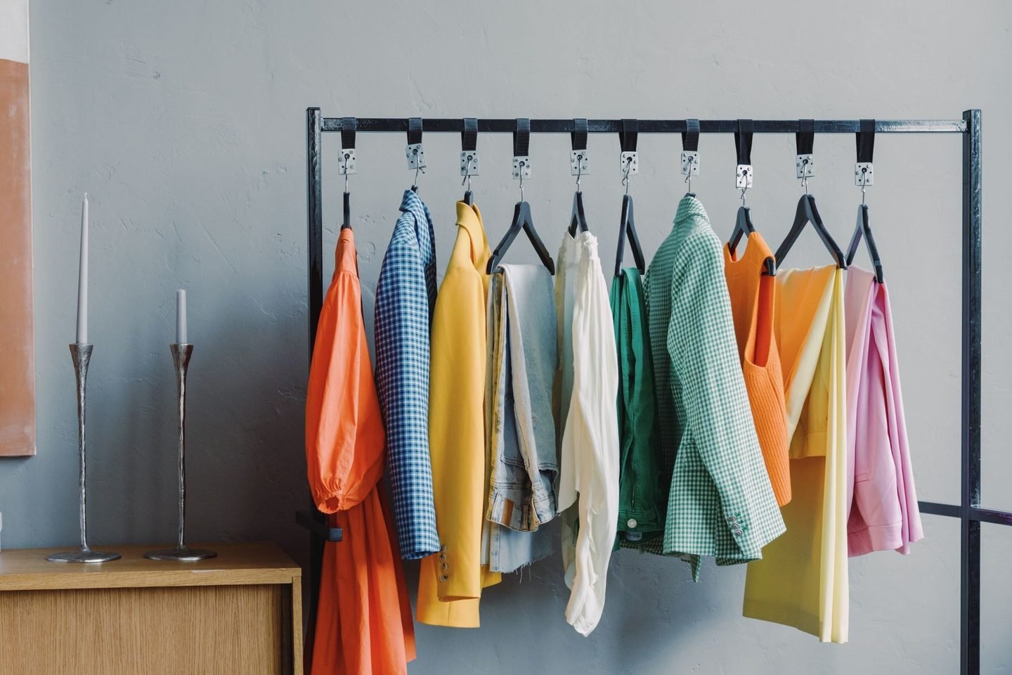 Arara preta com roupas coloridas penduradas, num quarto claro.